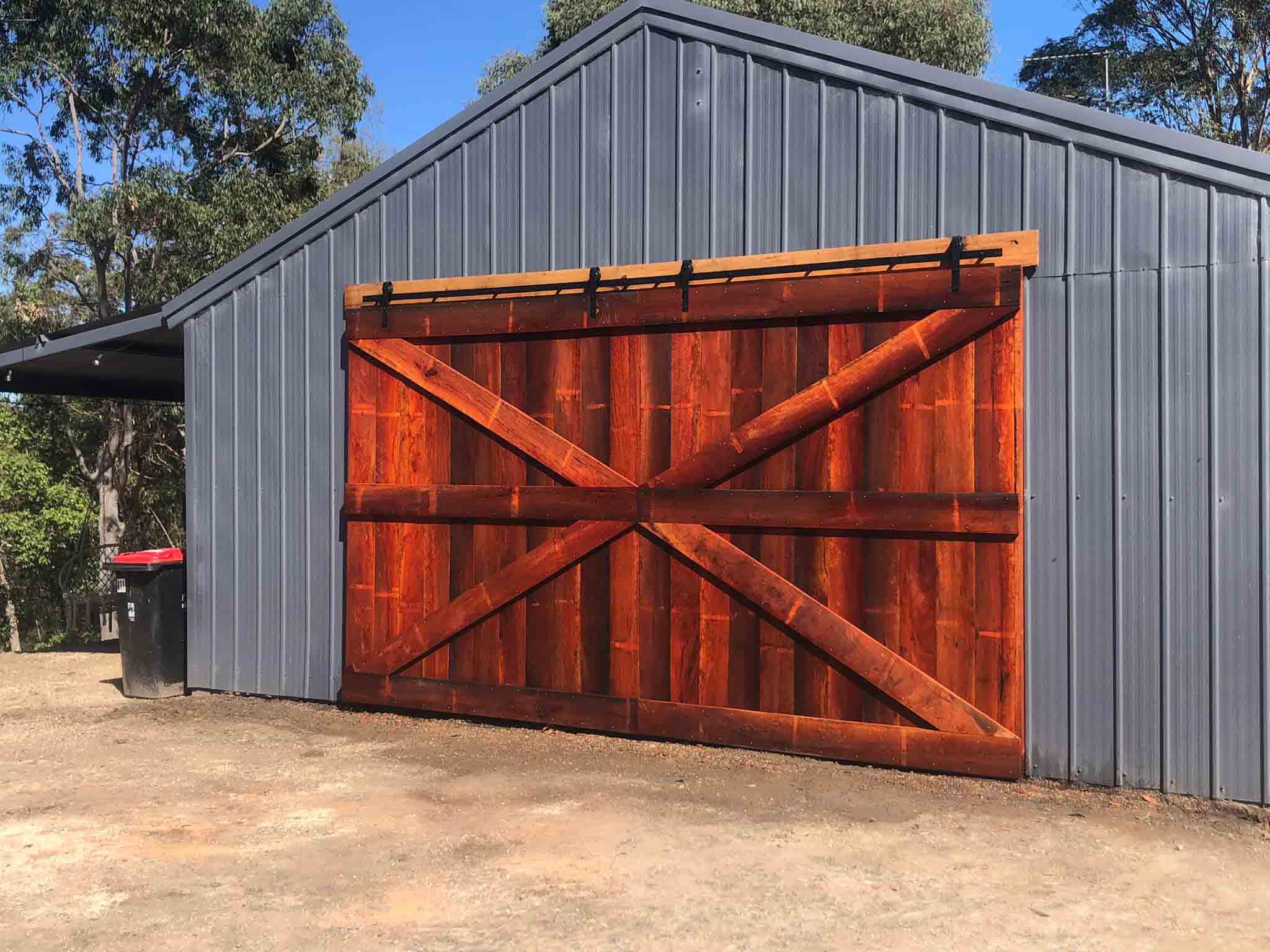 Large timber barn doors on the front of a grey steel shed