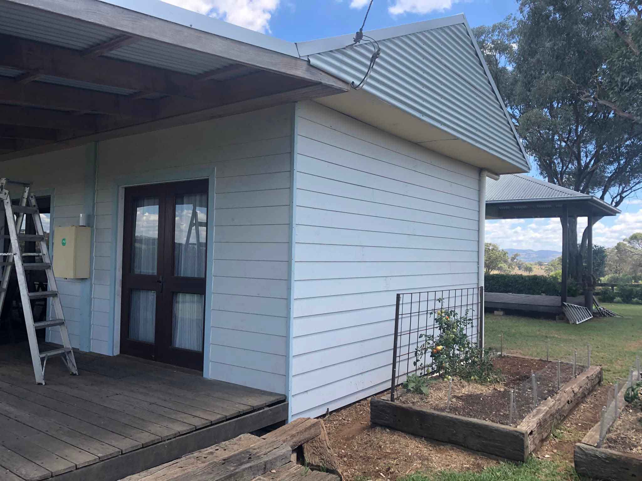 Weatherboard extension with timber French doors and a raised garden bed