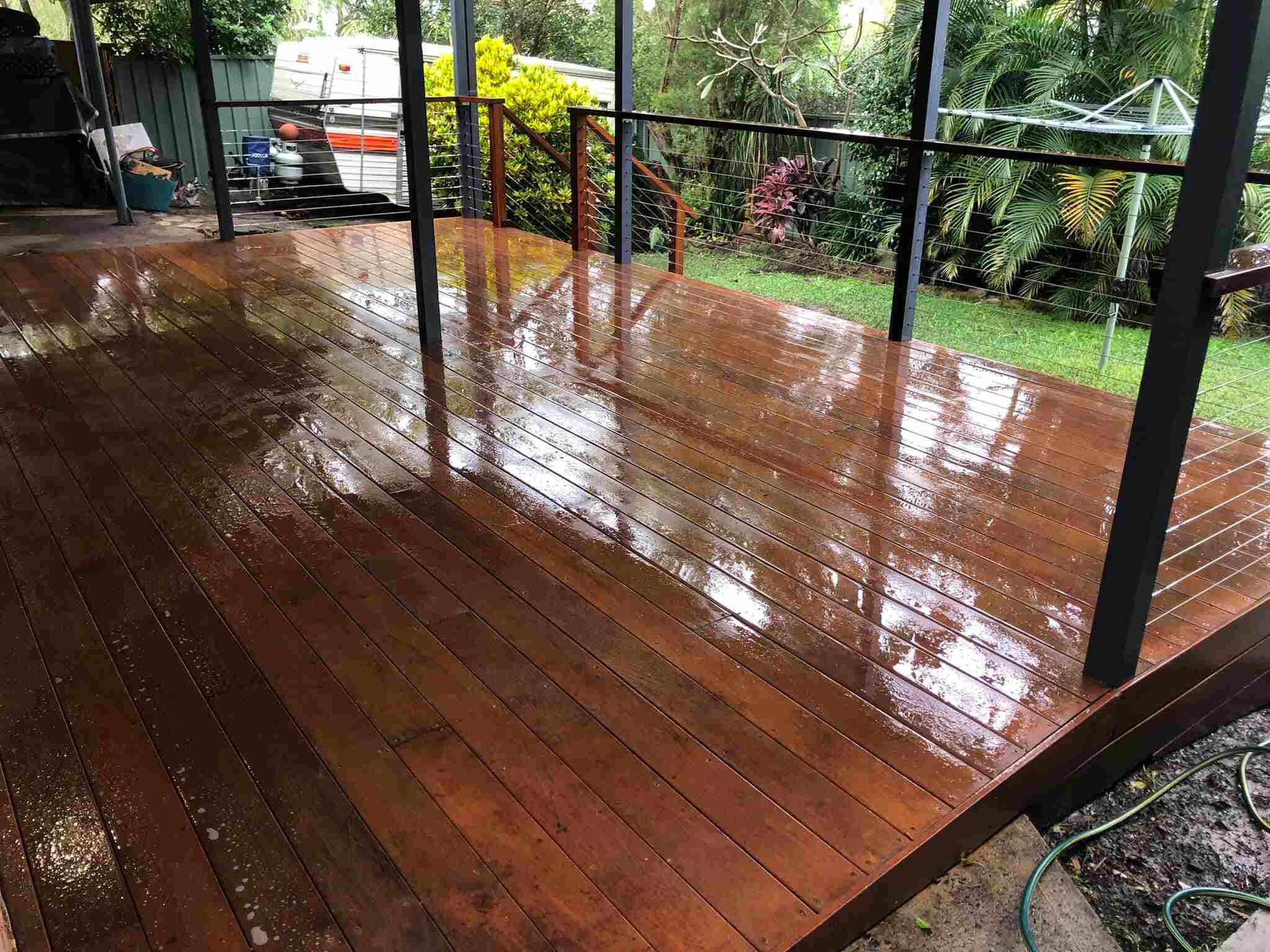 Glossy timber deck with wire balustrade under a pergola