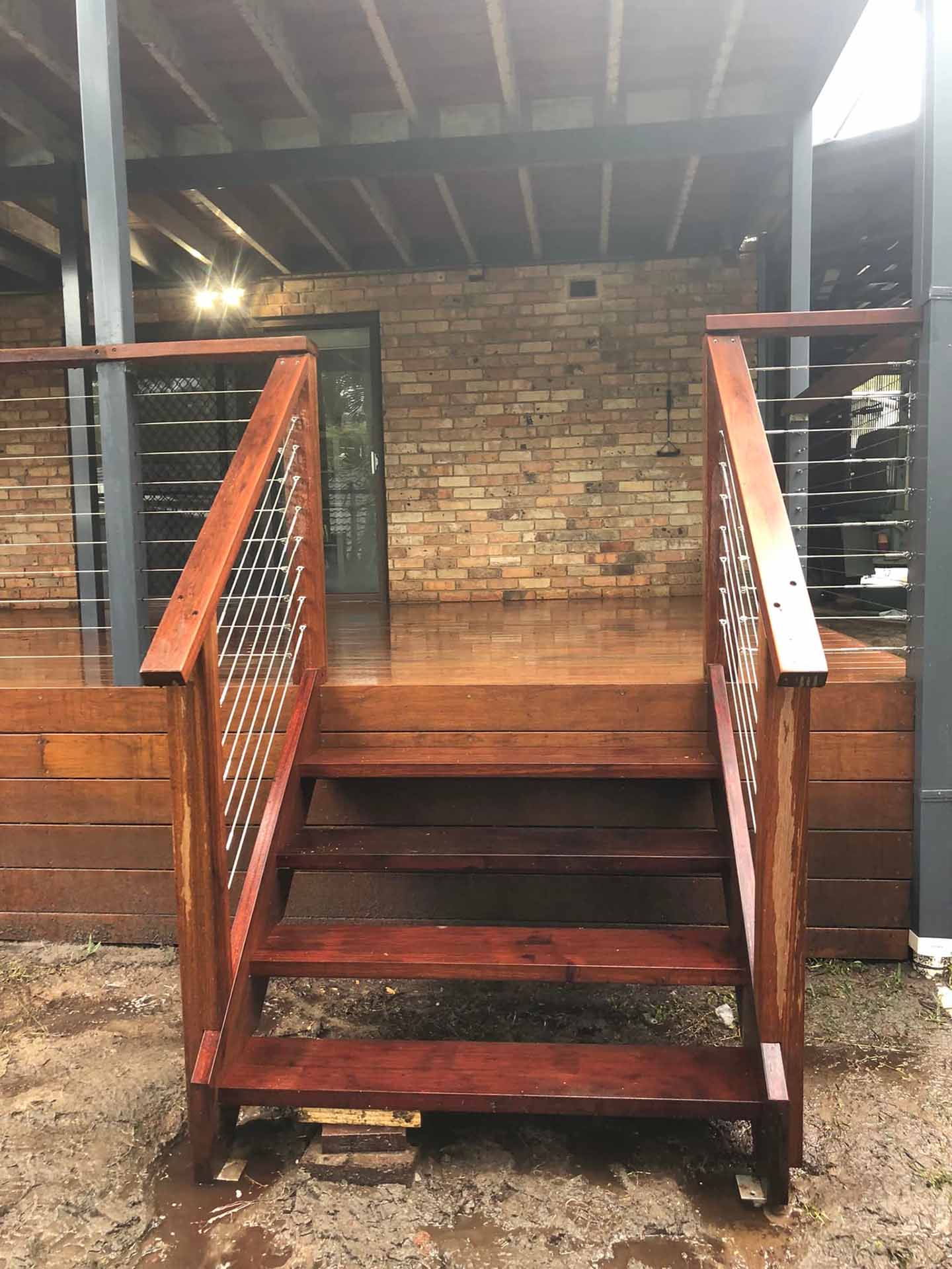Timber stairs with wire balustrade leading up to a covered deck