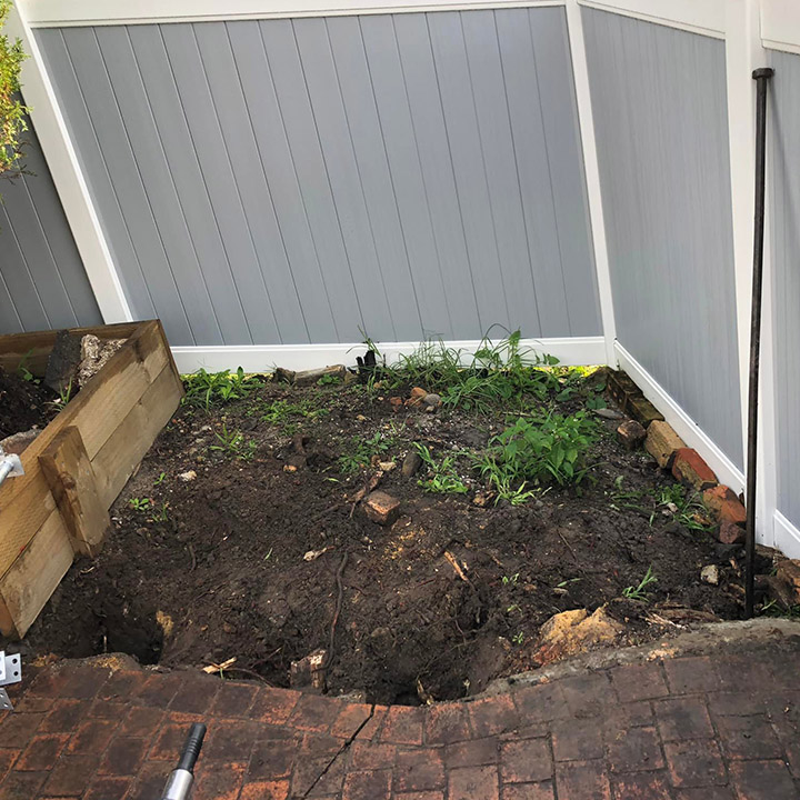 Before: bare garden bed in a fenced corner beside brick paving
