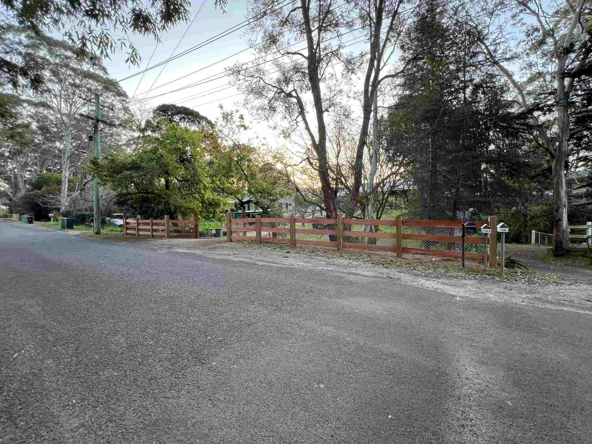 Long run of timber post-and-rail fencing beside a sealed road