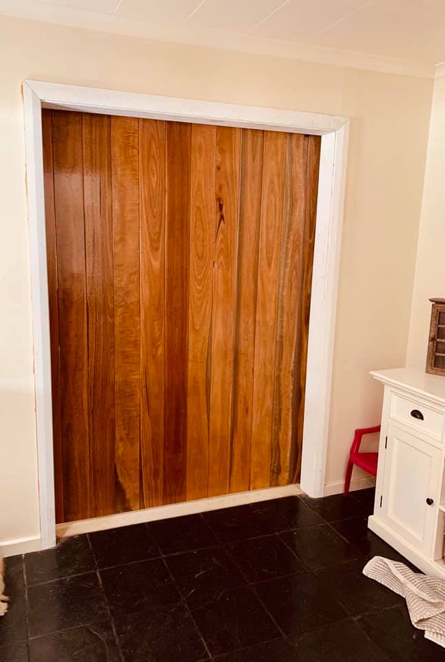 Tall timber doors set in a white doorway beside a white cabinet
