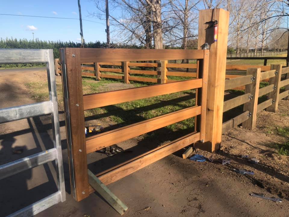 Timber gate post and rails with a metal gate swung open