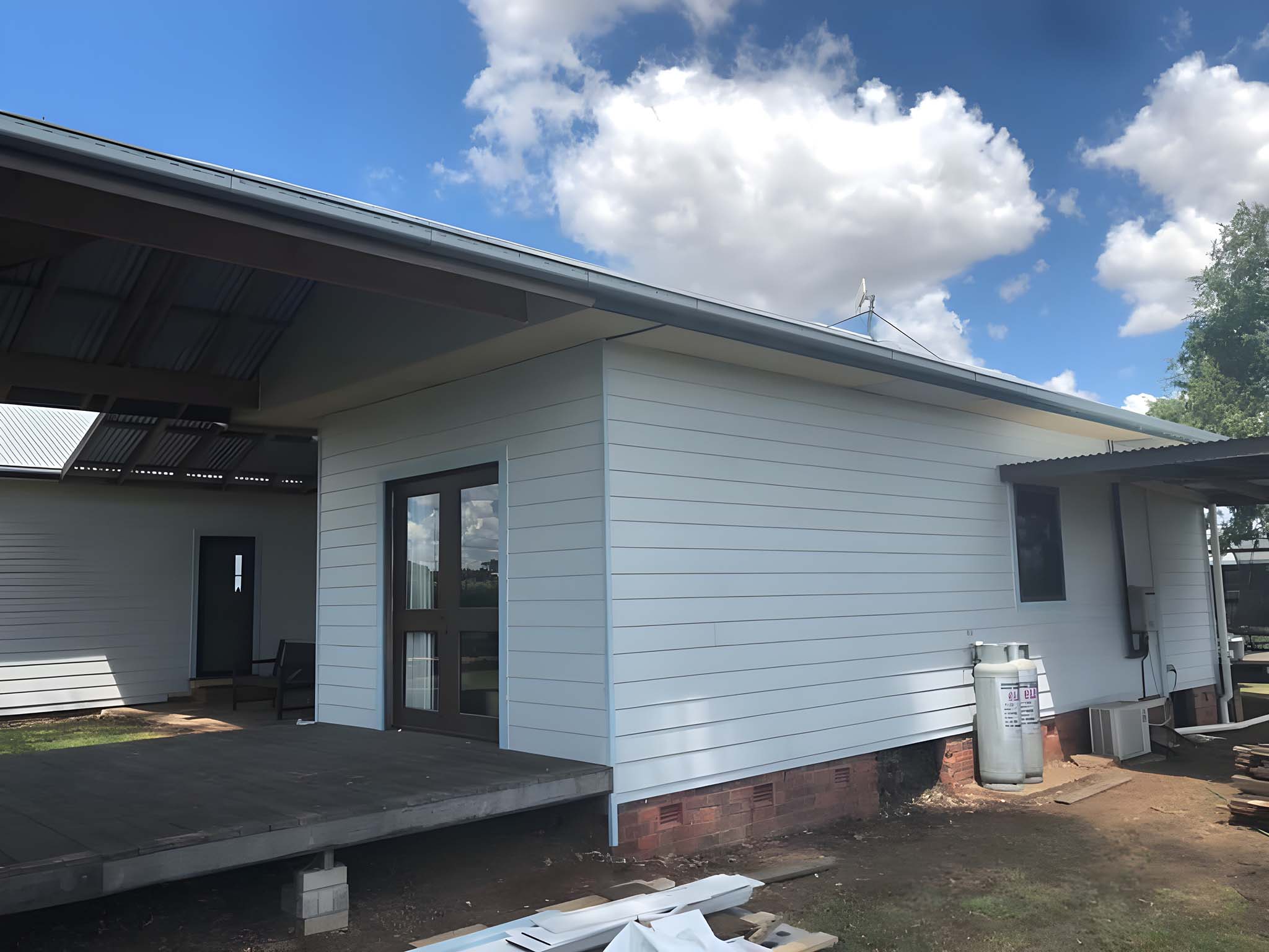 Weatherboard extension with a covered deck beside it
