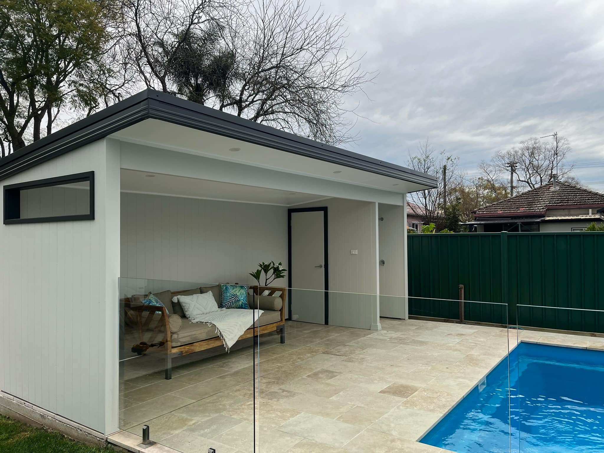 Pool cabana with a daybed behind glass pool fencing