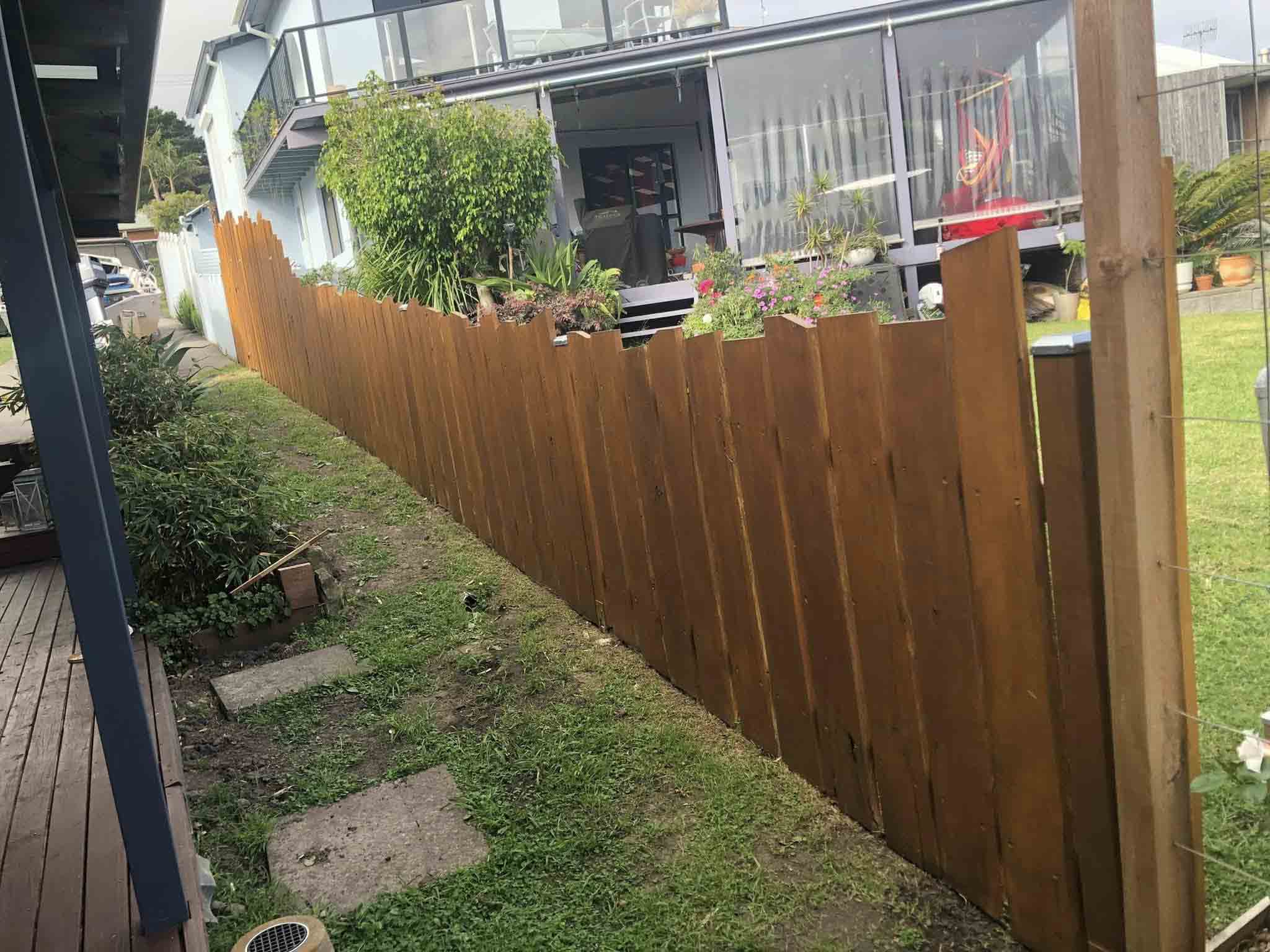 Stained timber paling fence beside a garden path and deck