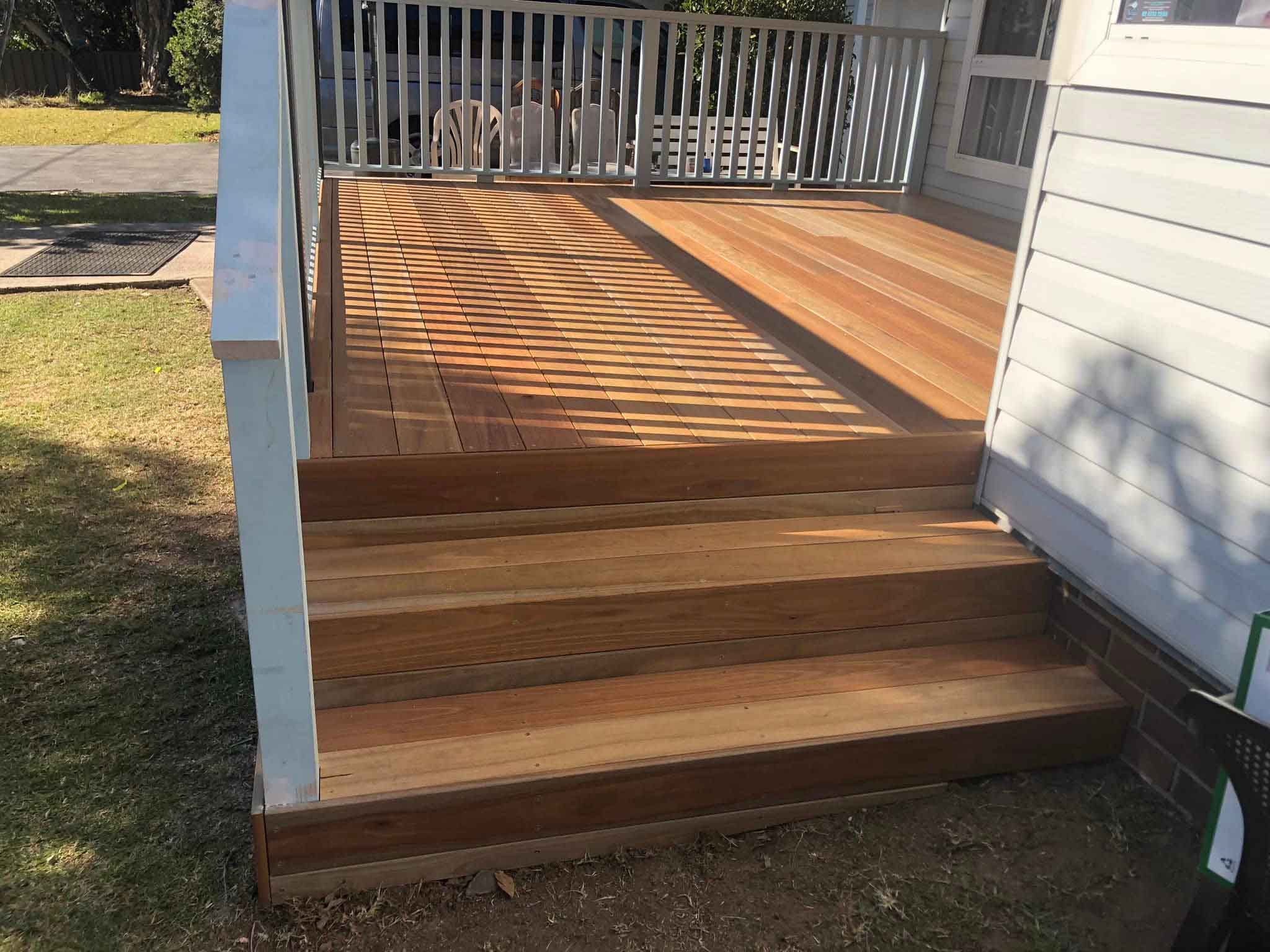 Freshly laid timber deck with wide steps beside a weatherboard house