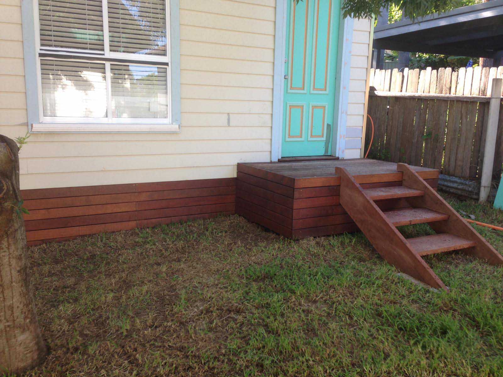 Timber landing and steps at a turquoise door with timber skirting