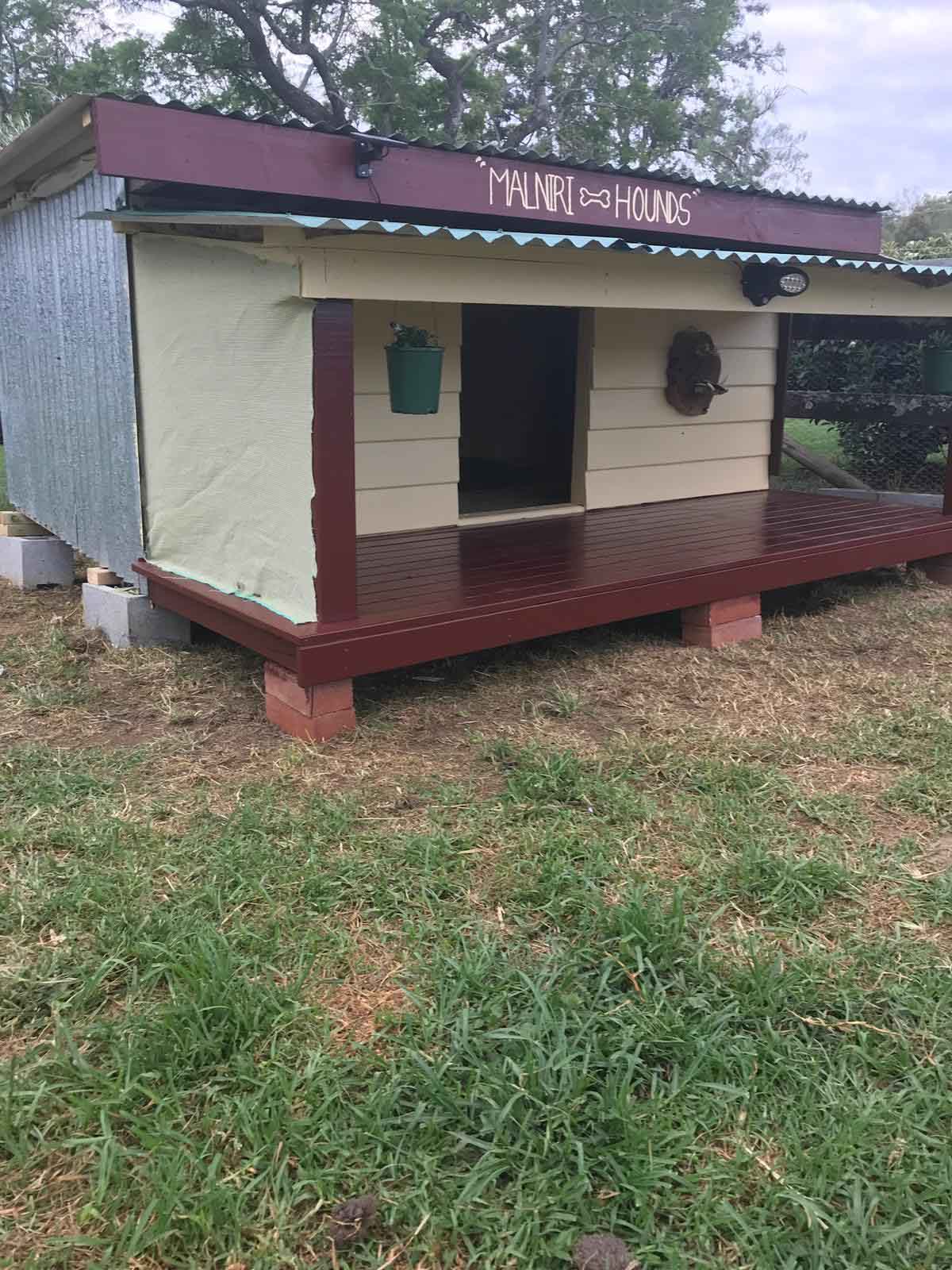 Large timber-framed dog kennel with a front deck and corrugated roof