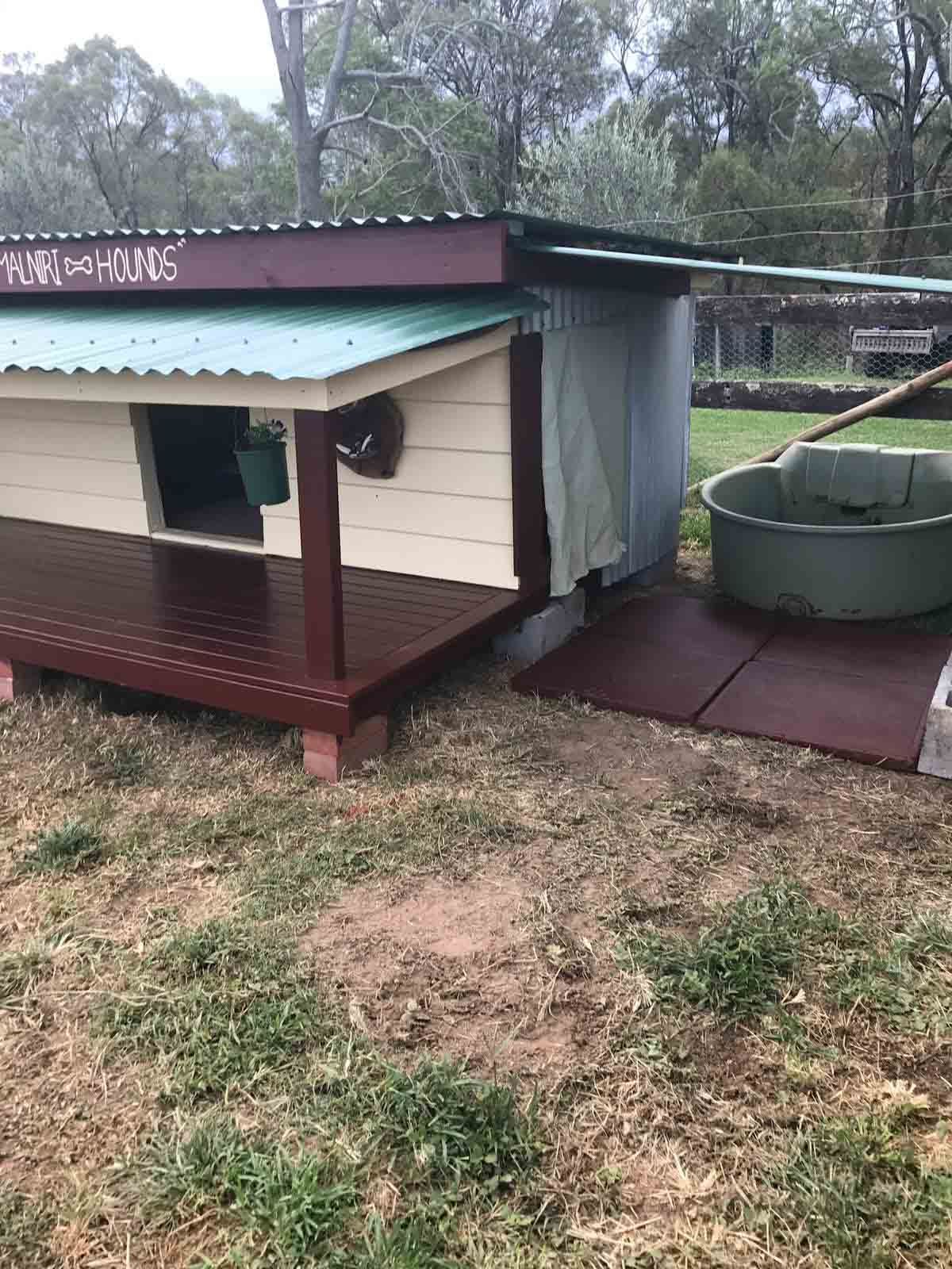 Side view of the dog kennel with its deck and a water tank