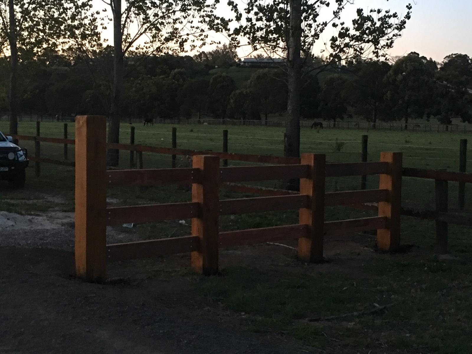 Close view of a new timber post-and-rail fence in a paddock at dusk