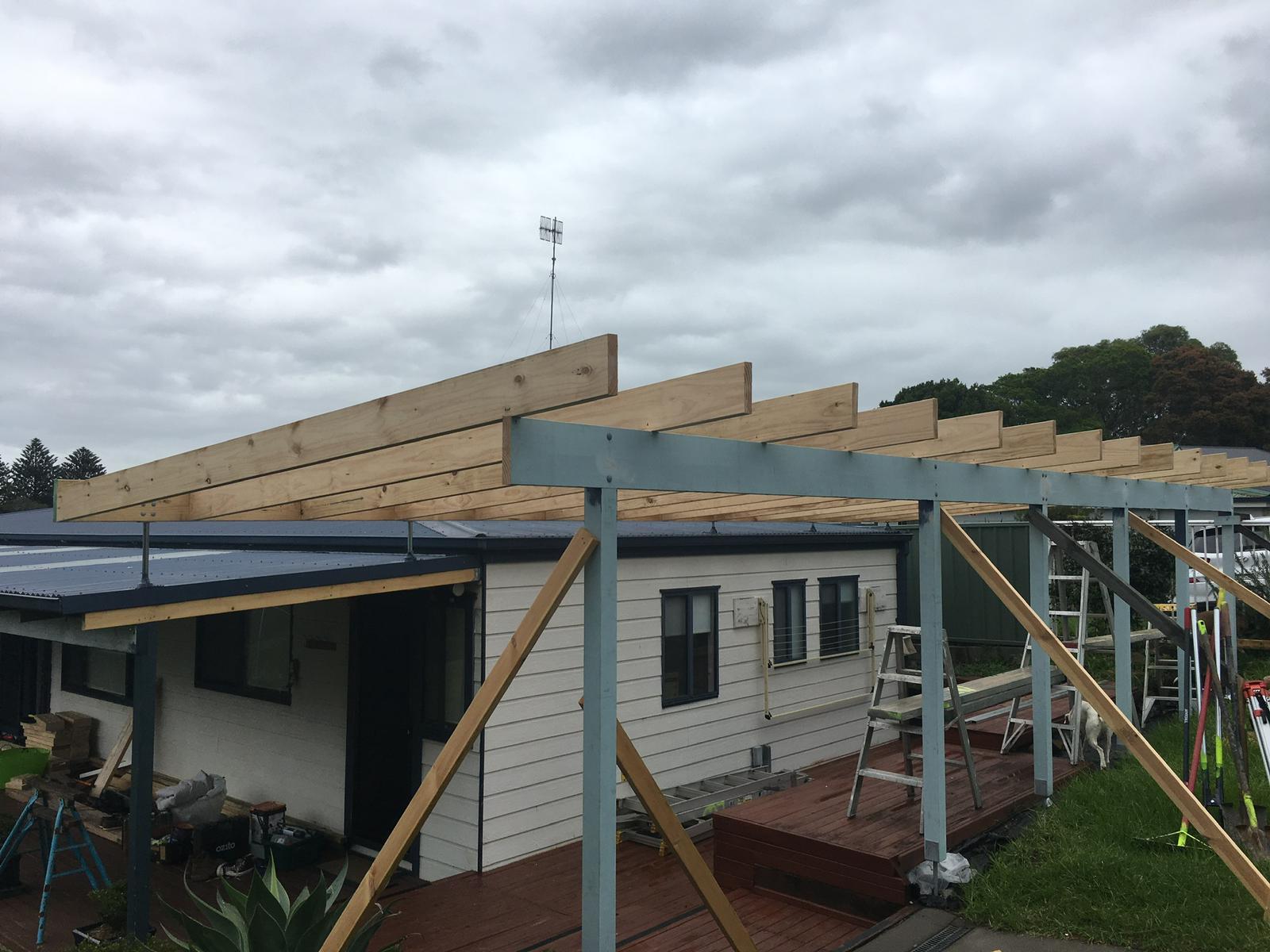 Timber rafters on a steel pergola frame being built over a deck
