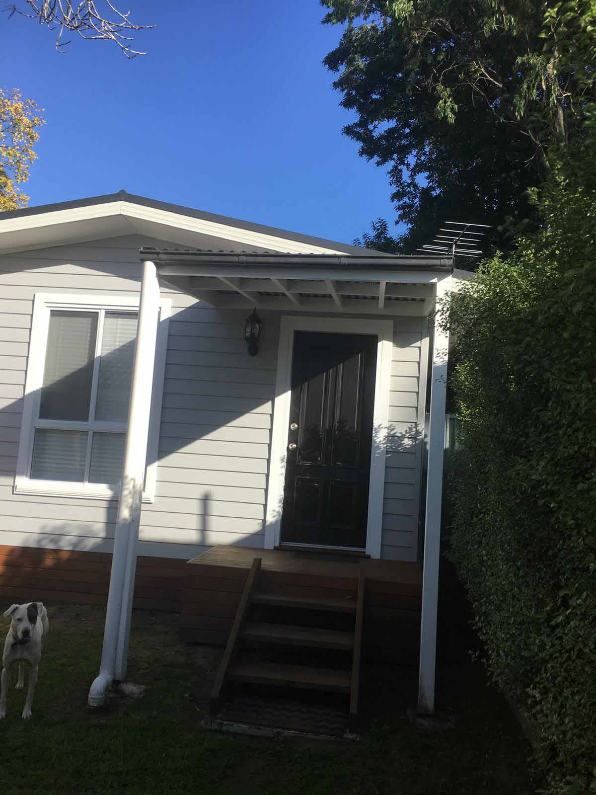 Timber steps up to a small covered porch on a weatherboard building