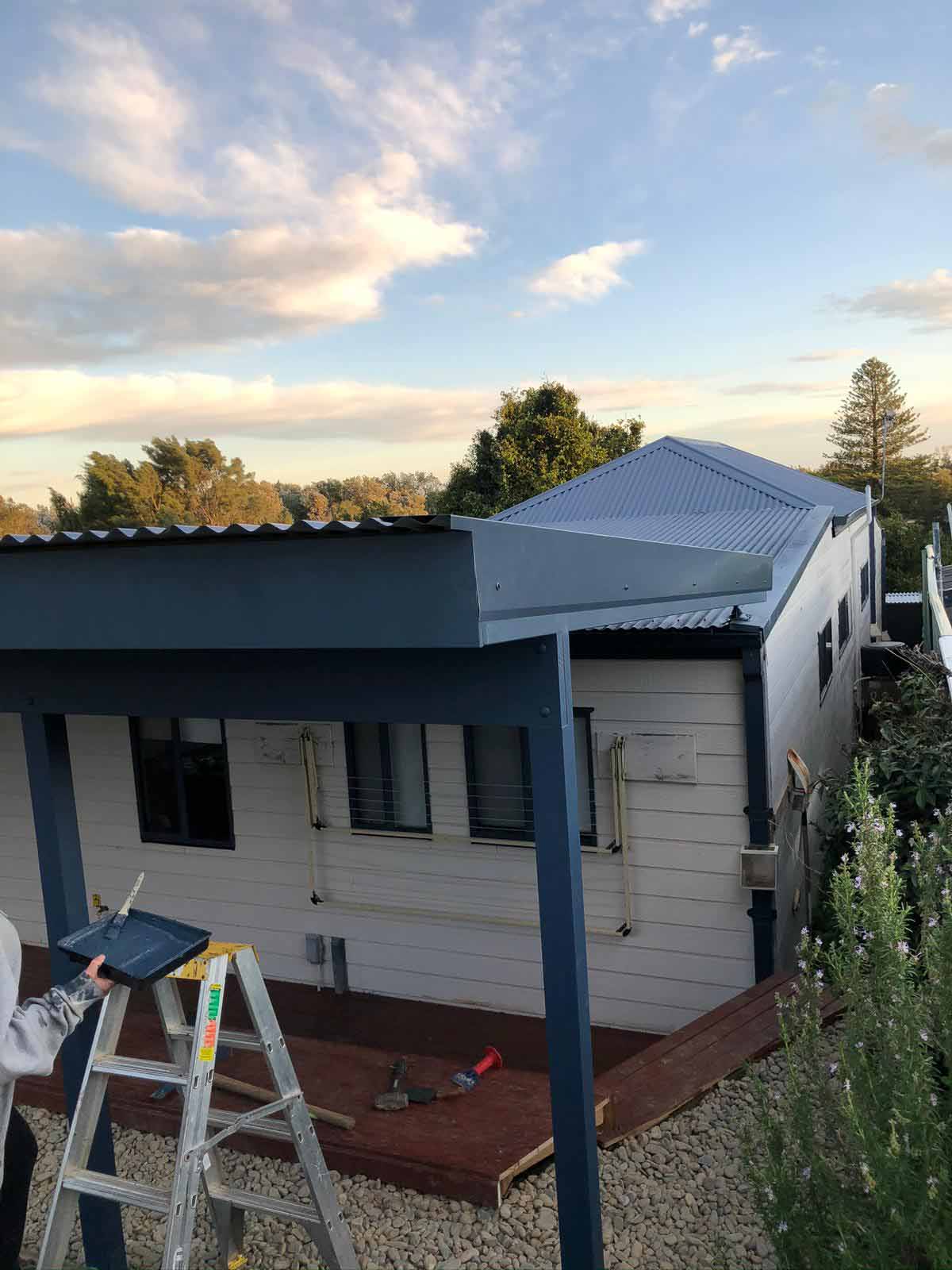 Covered deck under construction along a weatherboard house