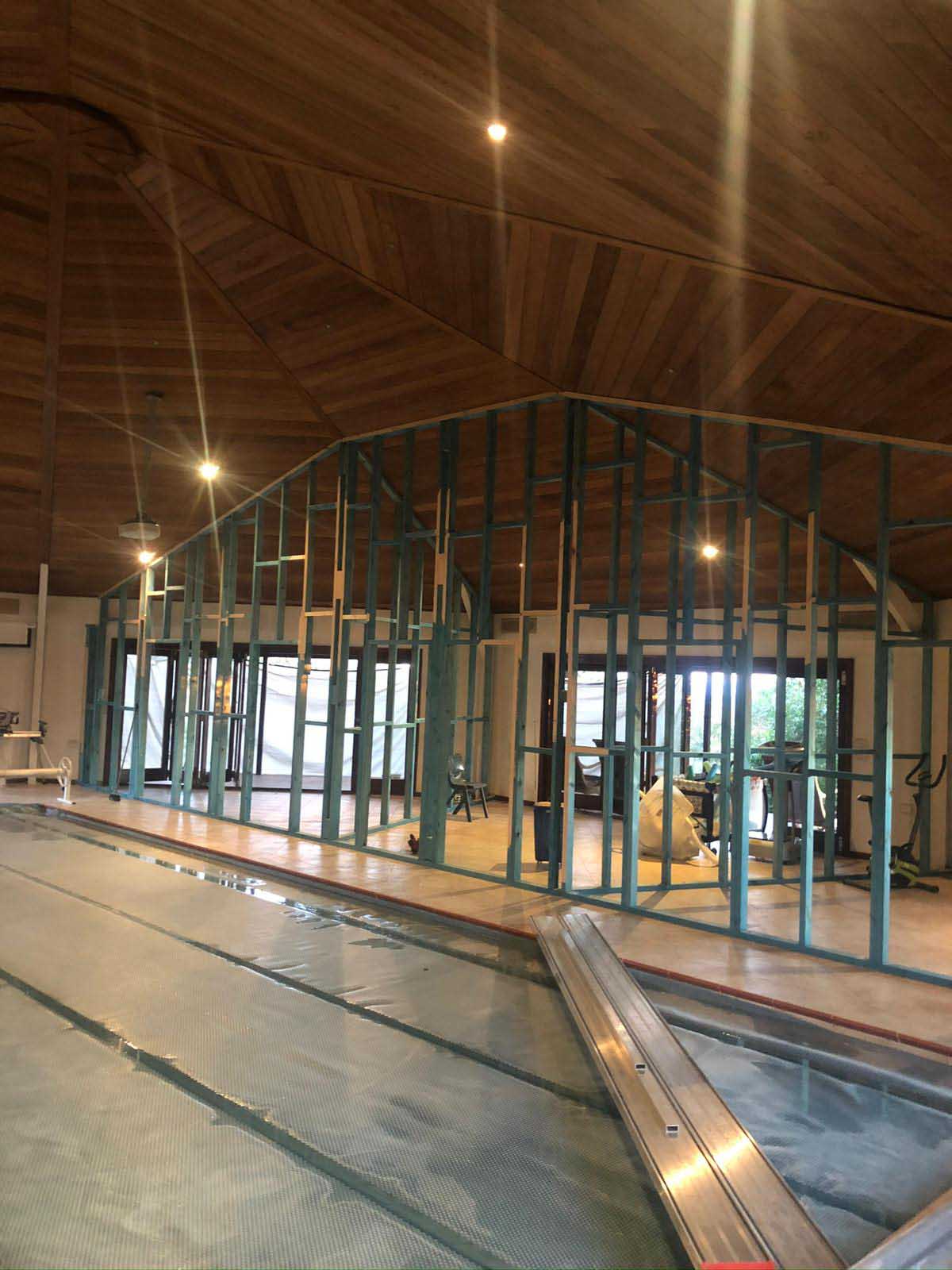 Steel wall frames going up under a timber-lined ceiling